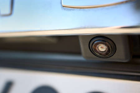 Car rear view camera parking sensor accessory reverse back new vehicle spycam with waterdrops. Luxury car rear view camera close up for parking assistance. Concept of safety car driving while parkingの写真素材