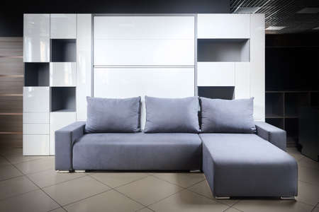Bedroom interior flat with folded Vertical Murphy WallBed rollaway pull out bed stared into wardrobe with shelves drawers and pillow front view, minimalist interior design modern architecture concept.の写真素材