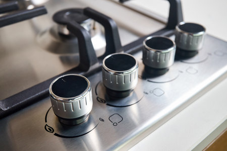 Hob cooker oven grill stainless steel control knobs selective focus over out of focus oven with burner background.の写真素材