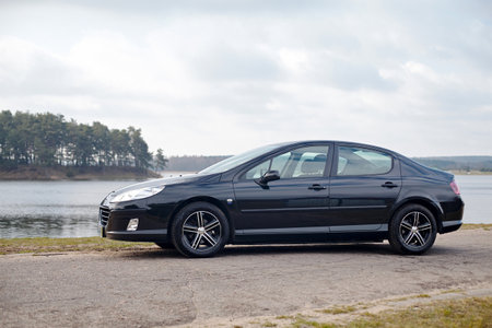 Berlin - April 2014: Peugeot 407 2003-2010 sedan pre facelift side view on road outdoors over spring landscape background with lake and forest with copyspace.のeditorial素材