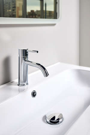Bathroom interior modern design sink under mirror with window reflection. Interior of bathroom with washbasin and faucet elongated rectangular shape bowl.の写真素材