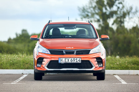 Berlin - July 2022: Kia Rio X 2021-2022 X-Line Burnt Orange parked in parking with forest and grass in background. Front view of compact hatchback Kia KX Cross.のeditorial素材