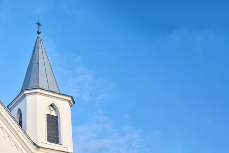 White church steeple with cross with window blind and cross over blue sky background. Religious easter background with copyspaceの写真素材