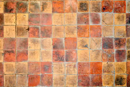Orange brown purple old shabby worn out floor tiles with damages cracks dirt caverns potholes and paint stains. Art design background texture.の写真素材