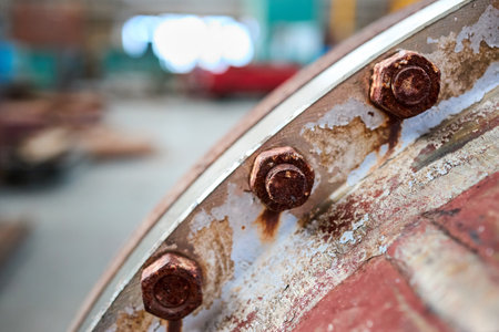Old rusty sealing connection bolted screw connection, on manhole of industrial machine compressor or pump on chemical plant selective focus with out of focus abstract industrial background, copyspace.の写真素材