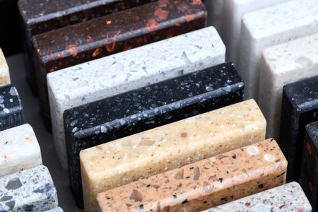 Porcelain stoneware square samples laid on kitchen countertop as examples of future kitchen fasade exterior. Samples slabs of natural granite marble quartz for stone countertops close up.の写真素材