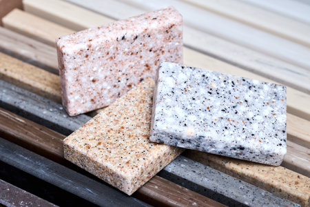 Porcelain three stoneware square samples laid on kitchen countertop examples of future kitchen fasade exterior. Samples slabs of natural granite marble quartz for stone countertops close up.の写真素材