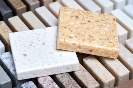 Porcelain two stoneware square samples laid on kitchen countertop examples of future kitchen fasade exterior. Samples slabs of natural granite marble quartz for stone countertops close up.の写真素材