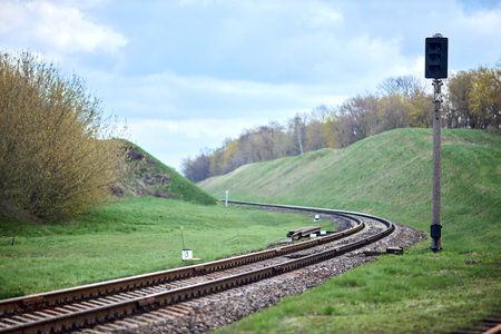 Selective focus railway lantern of semaphore railroad enable, allow permit track that twists and turns between hills. Empty rounding and turning single track of railways.の写真素材