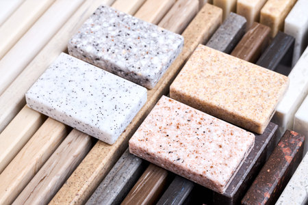 Porcelain four stoneware artificial stone square samples laid on kitchen countertop examples of future kitchen fasade exterior. Samples slabs of natural granite marble quartz for stone countertops.の写真素材