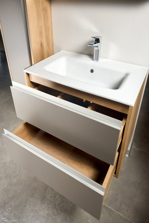 Solutions for placing things in bathroom horizontal sliding pull out drawer shelves storage in a cupboard under stoneware washbasin cabinet under sink and faucet. Modern loft flat minimalistic design.の写真素材