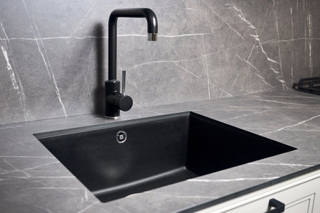 Kitchen sink area with black square matte sink tap in contemporary style. Matte black and stoneware countertop kitchen design.の写真素材