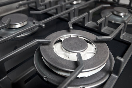 Wok burner with auto ignition of contemporary black tempered glass gas stove hob cast iron pan supports and flame safety valve.の写真素材