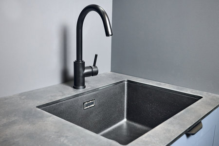 Blue grey contemporary kitchen linearlayout with hood two burners gas cooker hob oven and built in dishwasher machine and square black sink and tap compact high pressure laminate HPL countertop.の写真素材