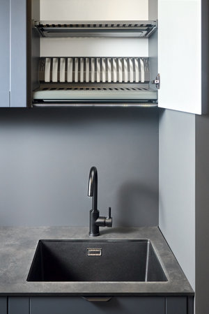 Single handle water filter kitchen faucet reverse osmosis or water filtration. Compact high pressure laminate HPL countertop undermount installation granite composite sink, opened dish drying cabinet.の写真素材