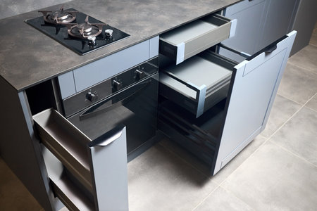 Vertical pull out rack cabinet drawer. Flush up slip handle finger pull handle of drawers for dishes, compact high pressure laminate HPL countertop, black glass gas stove cooker hob with two burners.の写真素材
