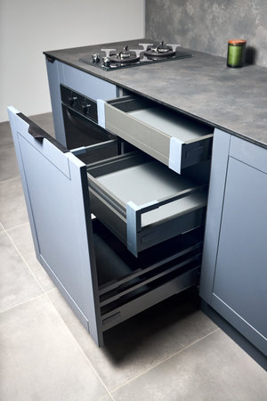 Vertical pull out rack cabinet drawer. Flush up slip handle finger pull handle of drawers for dishes, compact high pressure laminate HPL countertop, black glass gas stove cooker hob with two burners.の写真素材