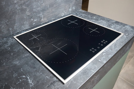 Flat cooktop cooking induction electric built black stove. Grey countertop with black glossy built in ceramic tempered glass induction or electric hob stove cooker with four burners in kitchen.の写真素材