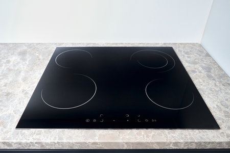 Flat cooktop cooking induction electric built black stove. Grey countertop with black glossy built in ceramic tempered glass induction or electric hob stove cooker with four burners in kitchen.の写真素材