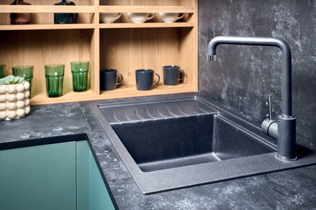 Interior of contemporary green and red kitchen. Luxury modern fitted flat design kitchen with square stoneware sink and tap wooden shelves cupboard sideboard with dish drying cabinet.の写真素材