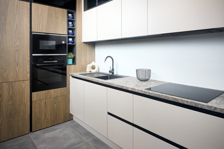 Urban rustic loft style kitchen interior in wooden facade and stoneware countertop tabletop with built-in appliances as induction stove hob cooker sink microwave oven and oven fridge dishwasher.の写真素材