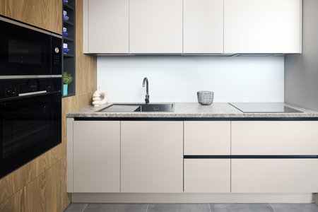 Urban rustic loft style kitchen interior in wooden facade and stoneware countertop tabletop with built-in appliances as induction stove hob cooker sink microwave oven and oven fridge dishwasher.の写真素材
