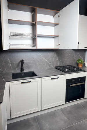 Interior of white and grey kitchen, horizontal linear layout. Luxury modern fitted flat design kitchen with opened cupboard shelves sideboard with dish drying cabinet vertical shot.の写真素材