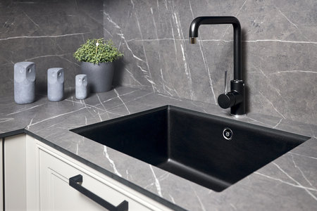 Single handle water kitchen faucet built in compact high pressure laminate HPL countertop. Kitchen undermount installation granite composite sink.の写真素材