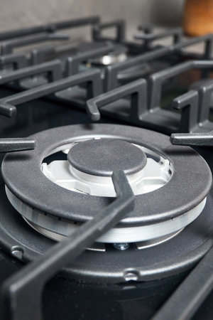 Wok burner with auto ignition of contemporary black tempered glass gas stove hob cast iron pan supports and flame safety valve. Vertical closeup shot.の写真素材
