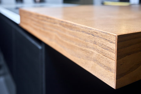 Solid ash glued timber under varnish edge corner table top selective focus macro closeup. Kitchen interior contemporary design countertop tabletop.の写真素材