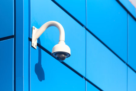 Panoramic adaptive dome CCTV camera with IR illuminators and artificial intelligence for wide area coverage and mega zoom mounted on blue aluminum composite panels facade of commercial building.の写真素材