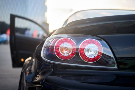 Berlin, Germany - August 20, 2022: Car Detail Shot of Mazda RX-8. Rearlight of black metallic car shot closeup with opened door out of focus background with copyspace.のeditorial素材