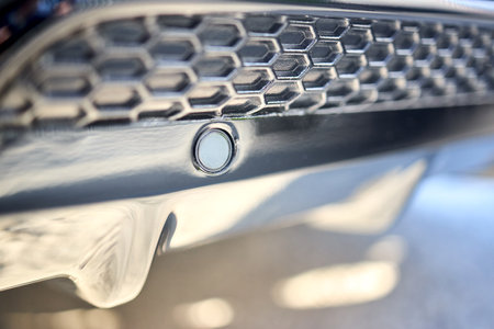Selective focus on left side of rear bumper parking sensor at back of luxurious car bumper close up on grid background with copyspace.の写真素材