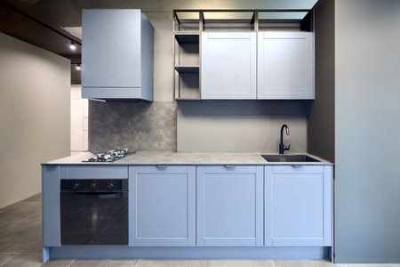 Blue gray contemporary kitchen linearlayout with hood, two burners gas cooker hob oven and built in dishwasher machine, square black sink and tap. Compact high pressure laminate HPL countertopの写真素材