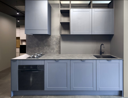 Blue gray contemporary kitchen linearlayout with hood, two burners gas cooker hob oven and built in dishwasher machine, square black sink and tap. Compact high pressure laminate HPL countertopの写真素材