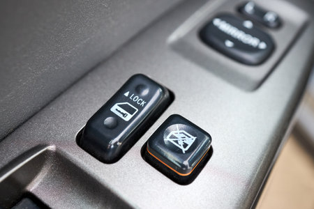 Modern hybrid electric car closeup interior detail. Driver door control panel in armrest with window control panel, lock button, and mirror control.の写真素材