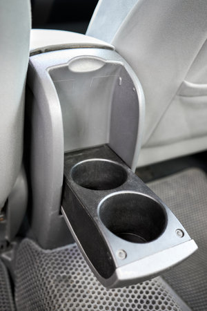 Cup holder modern electric hybrid car interior element. Grey leather rear passenger seat console with details closeup shot.の写真素材