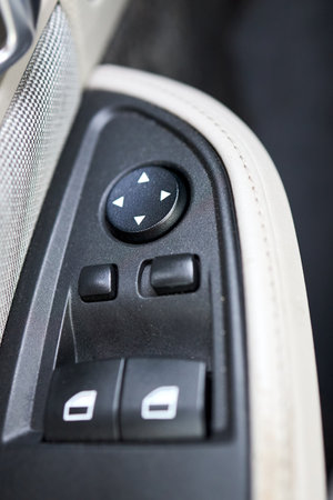 Modern hybrid electric car closeup interior detail. Driver door control panel in armrest with window control panel, lock button, and mirror control.の写真素材