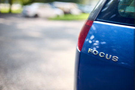 Minsk, Belarus - August, 24 2024: Ford Focus model of german Ford brand rear logo shield badge closeup selective focus shot over out of focus parking backgroundのeditorial素材