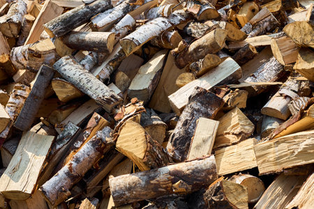 Stack of birch firewood with hand chopping block. Chopped firewood for winter. Lot of firewood - harvesting wood for heating the house. Horizontal photo. Chopped firewood background and textureの写真素材