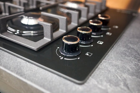 White hob cooker oven grill control knobs selective focus over out of focus oven with burner backgroundの写真素材