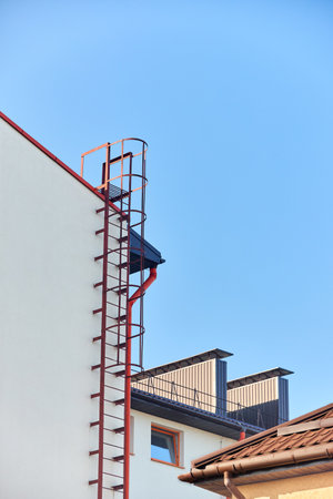 Secure stairs to the roof of the building. Metal. Red. Industrial building vertical shotの写真素材