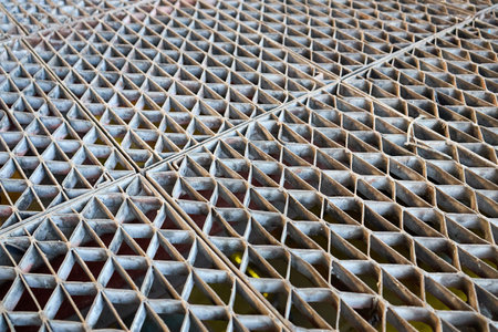 Metal industry steel grade sheet or floor grating with multicolored drops of paint macro closeup. Shallow depth of field diminished perspective industrial grates profiled drainage latticed flooring.の写真素材