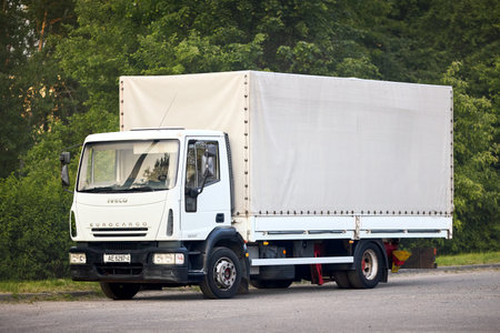 Minsk, Belarus - May, 28 2023: Iveco EuroCargo 120E21 Second generation 2002-2015 medium duty truck produced by Italian manufacturer Iveco. White truck parked in street over green foliage background.のeditorial素材