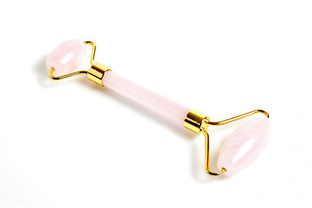 Pink Gua Sha massage tool over white background, close up focus stacking shot. Rose Quartz jade roller. Facial skin care at home, anti-aging and lifting therapy.の写真素材