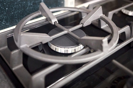 Gas stove burner burning with a blue flame. Modern gas stove for cooking. Close-up of a burning gas burner. The concept of problems with natural gas, rising prices and financial losses.の写真素材