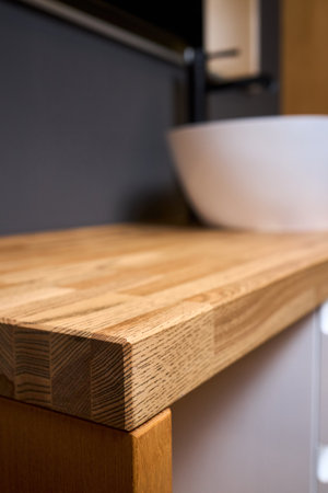 Solid ash glued timber under varnish edge corner table top selective focus macro closeup. Bathroom interior contemporary design countertop tabletop with sink.の写真素材