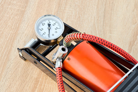 Orange foot air pump with gauge for car bicycle or bike part on wooden background close up shotの写真素材