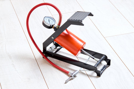 Orange foot air pump with gauge for car bicycle or bike part on wooden background close up shotの写真素材