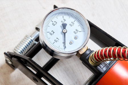 Orange foot air pump with gauge for car bicycle or bike part on wooden background close up shotの写真素材